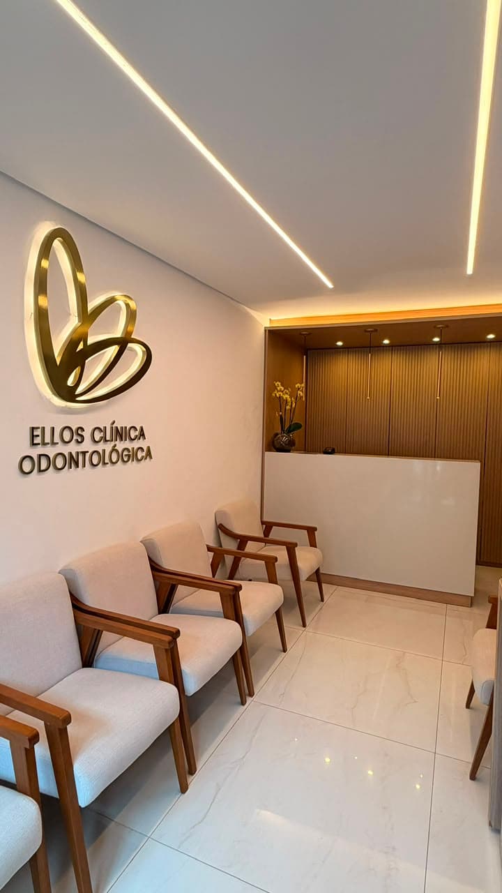 Recepção da Ellos: painel ripado de madeira natural, orquídea branca e bancada minimalista sob luz âmbar